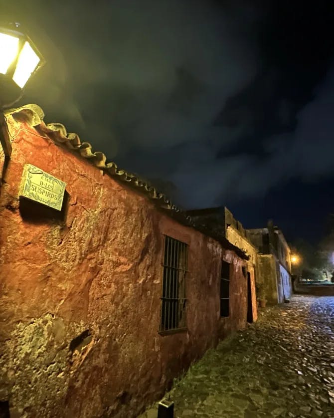 An old street with red building at lit by street lamps at night.