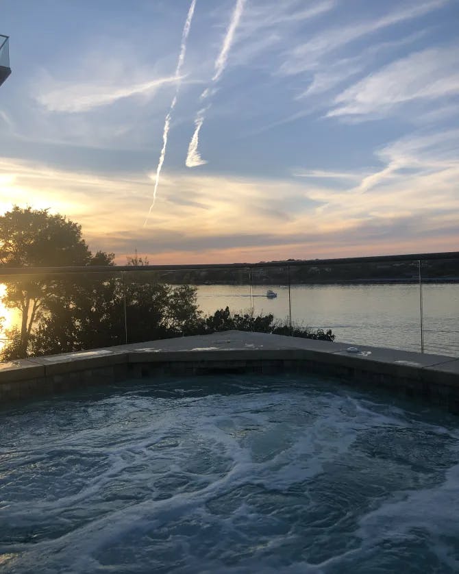 A jacuzzi overlooking a body of water at sunset