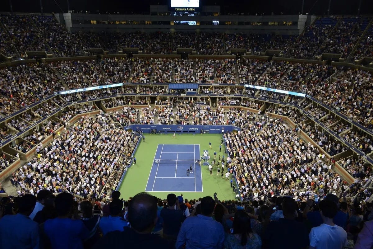 blue and green tennis court in the center of a stadium packed with people