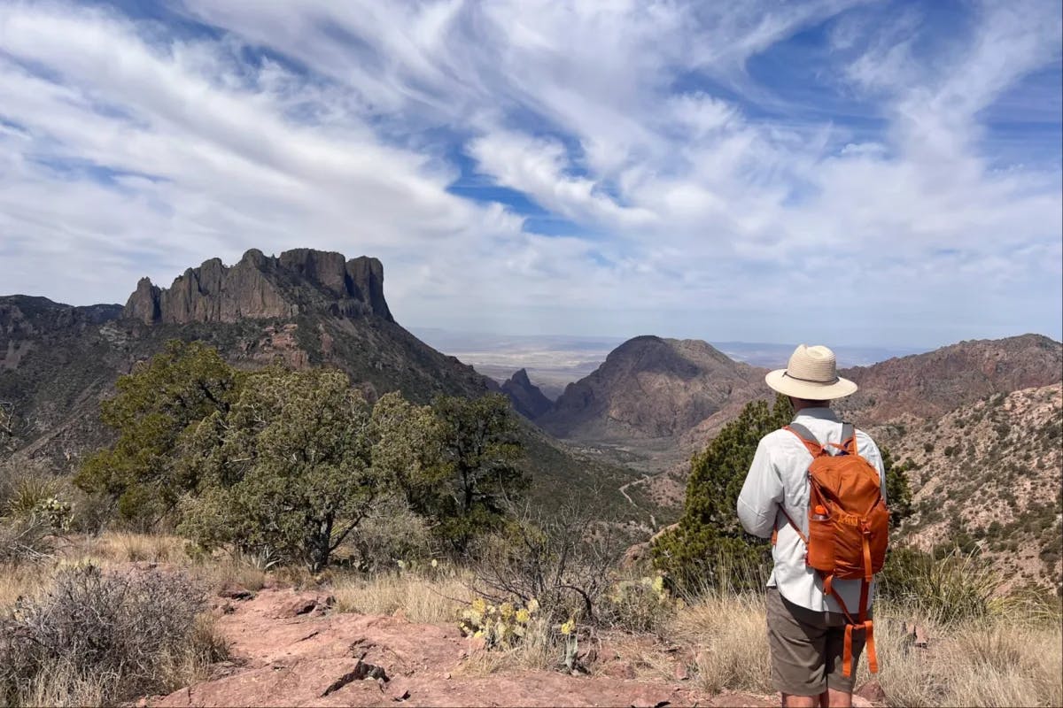 A person on a hiking trail with a view of hills in the background