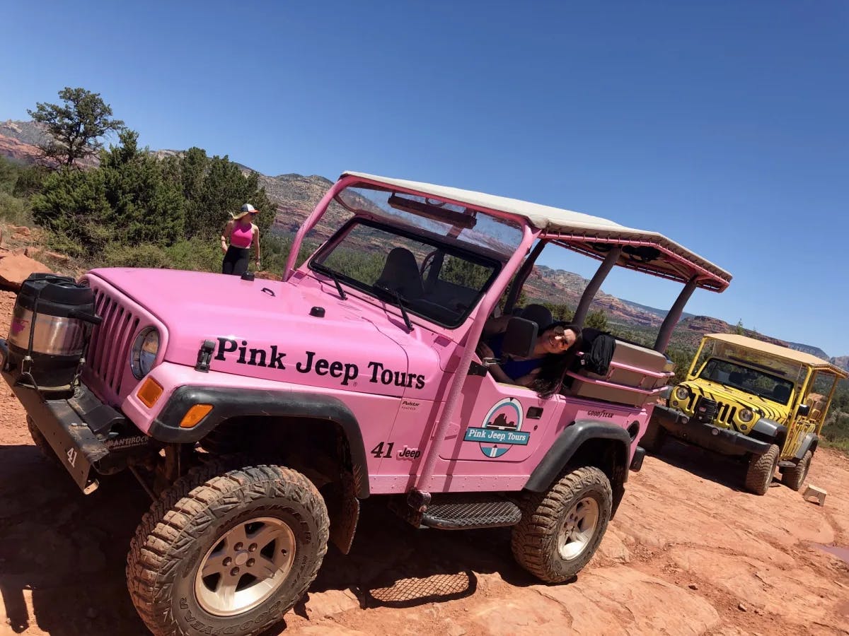 Pink and yellow jeep on a dry land.