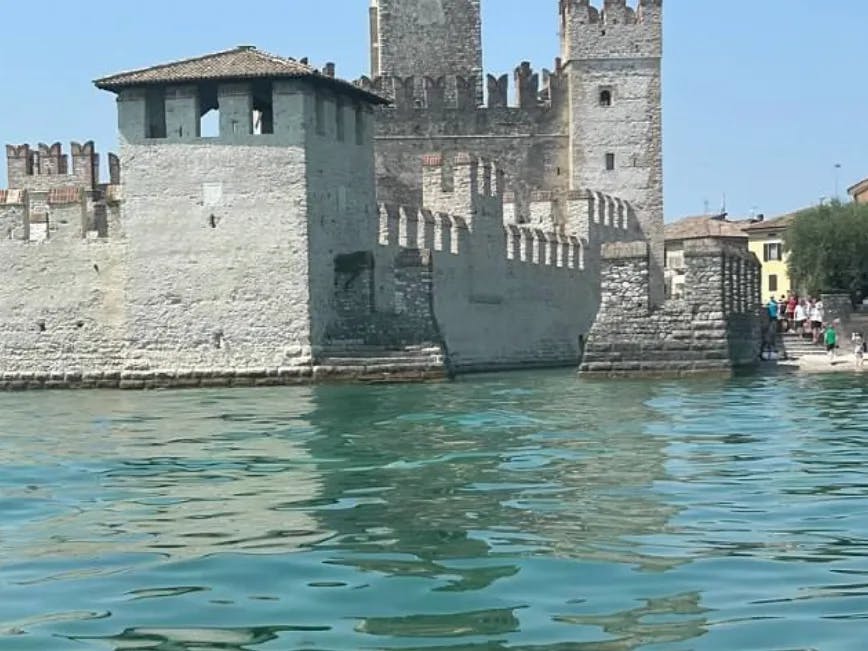 A stone castle against the reflective water in Italy. 