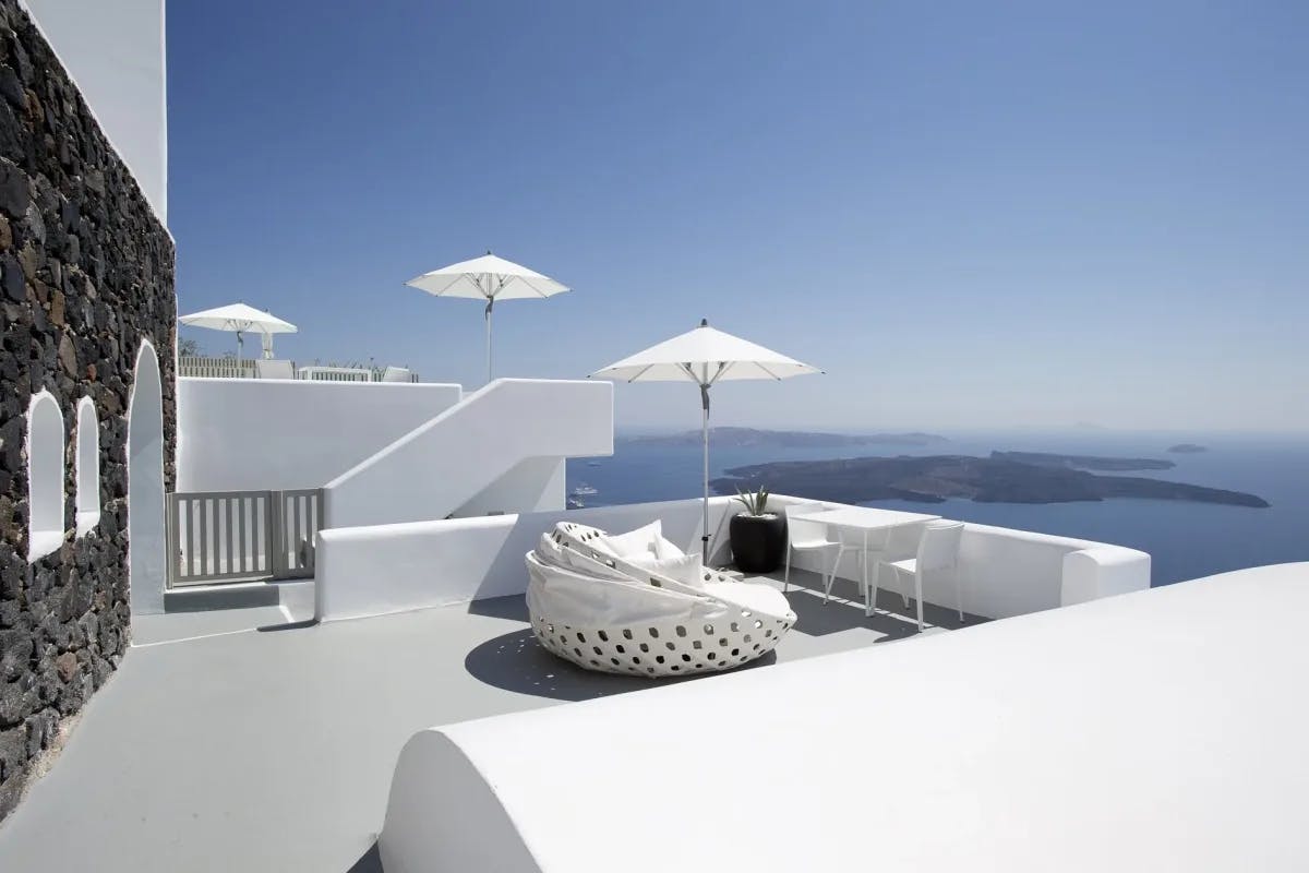 a circular daybed on a white balcony overlooking the ocean