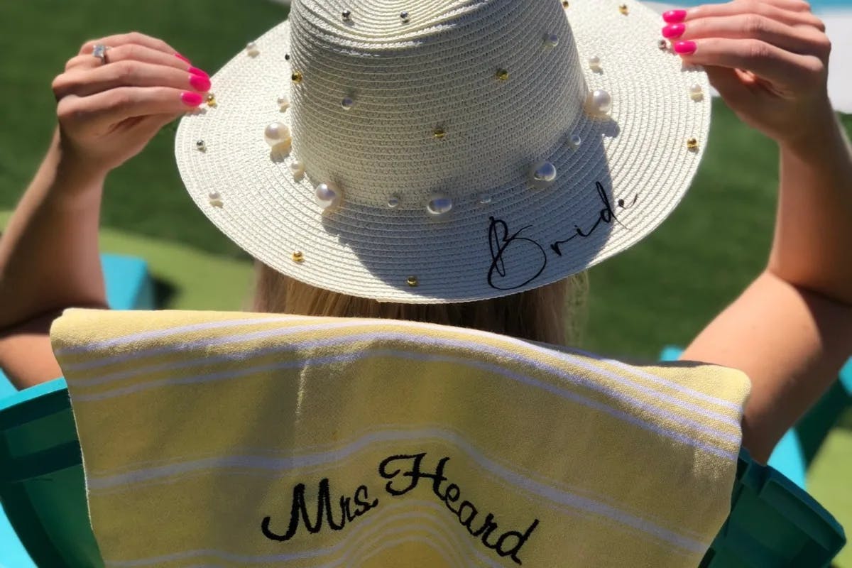 A person sitting in a white hat that says "bride" on the brim.