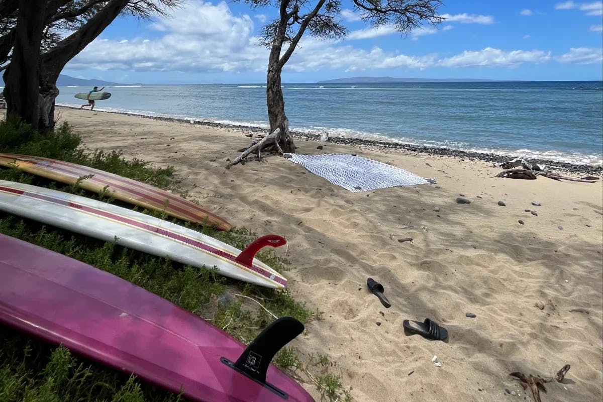 A far view of the beach with surfing boards lying at a corner during daytime.