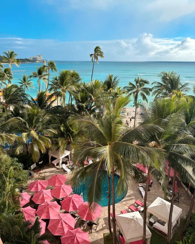 Poolside tranquility with a pop of color under pink umbrellas.