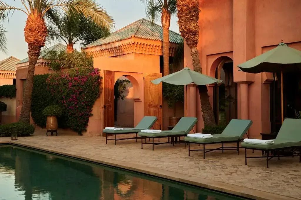 turquoise lounge chairs and umbrellas near a pool in a luxe courtyard