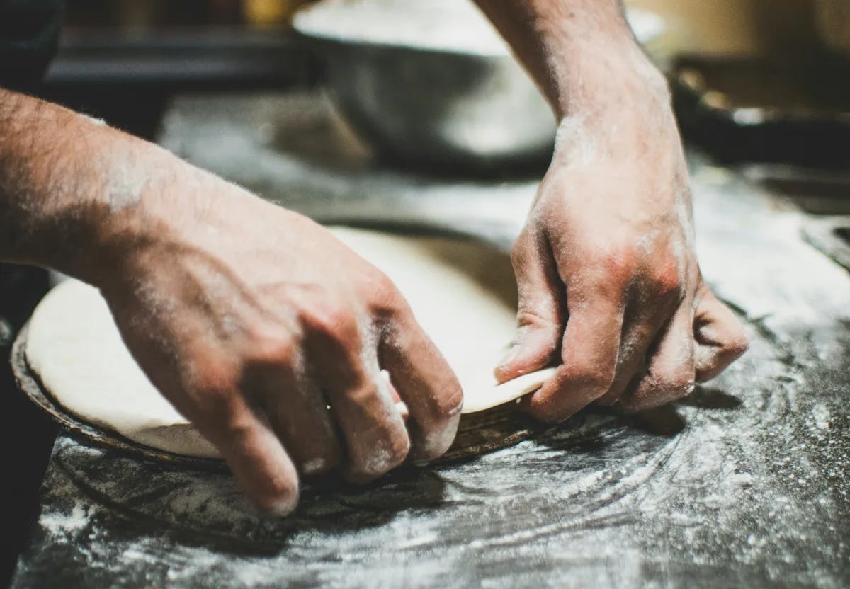 A person kneading dough on a table.