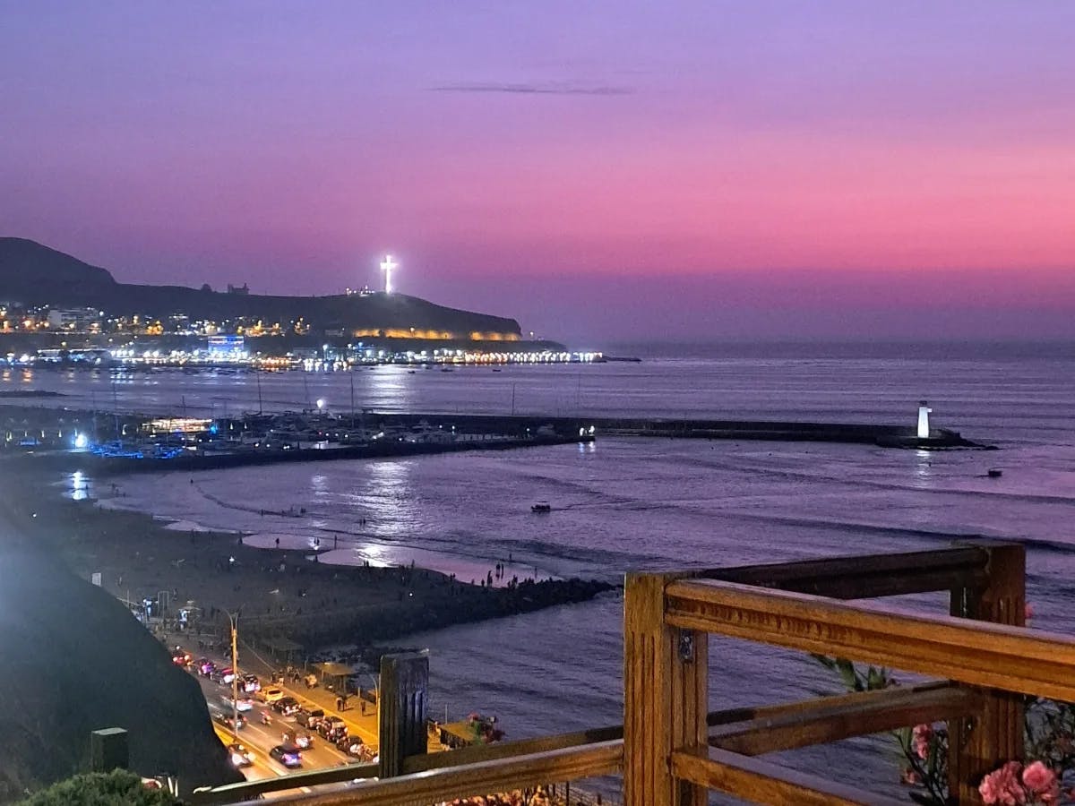 A beautiful view of a marina and city at sunset looking out to the sea. The sunset is exuding hues of pink and purple. 