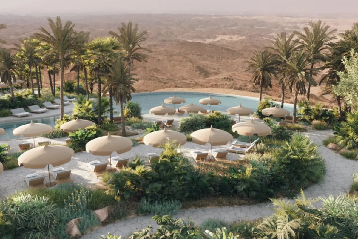 desert landscape with a resort pool surrounded by palm trees and pool umbrellas