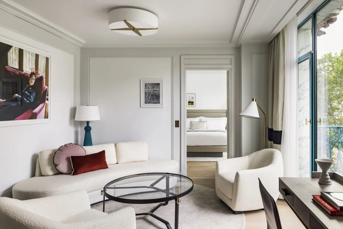 a large hotel room with a sleek living room filled with plush white furniture