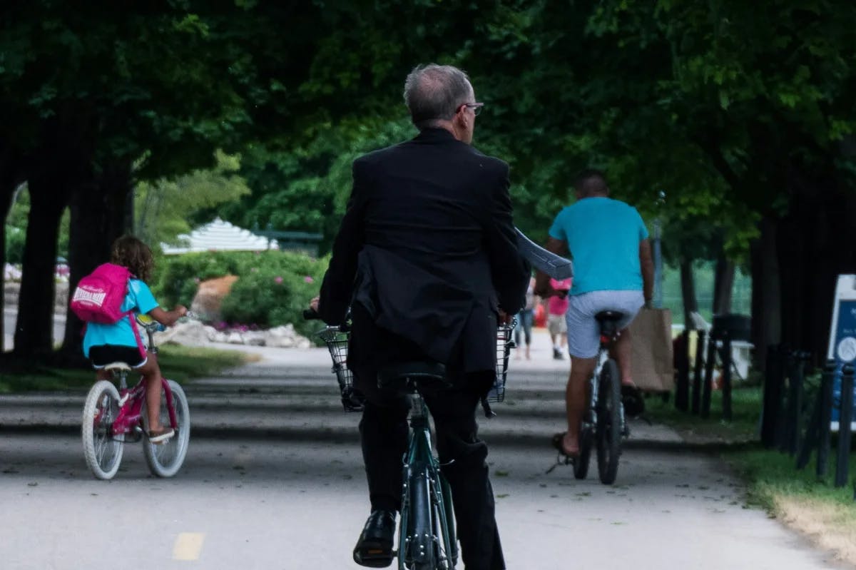 Older man on a bike on a tree-line bike path.