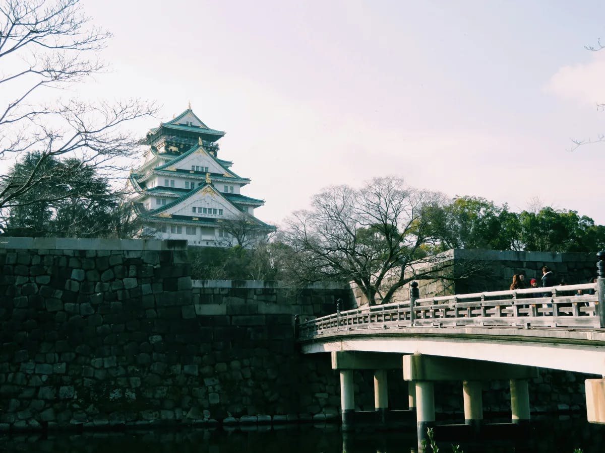 Osaka Castle across a river with a bridge in the foreground.