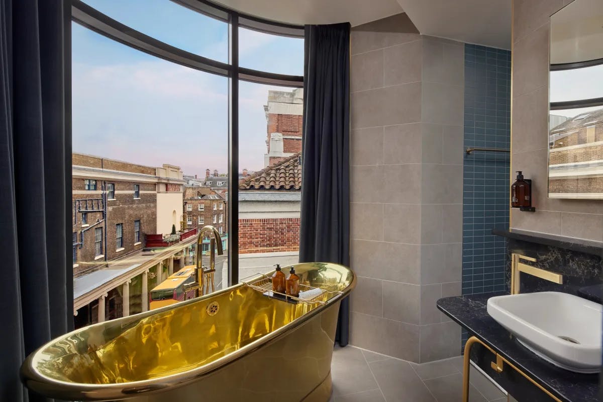 a gold bathtub near a large window in a modern bathroom