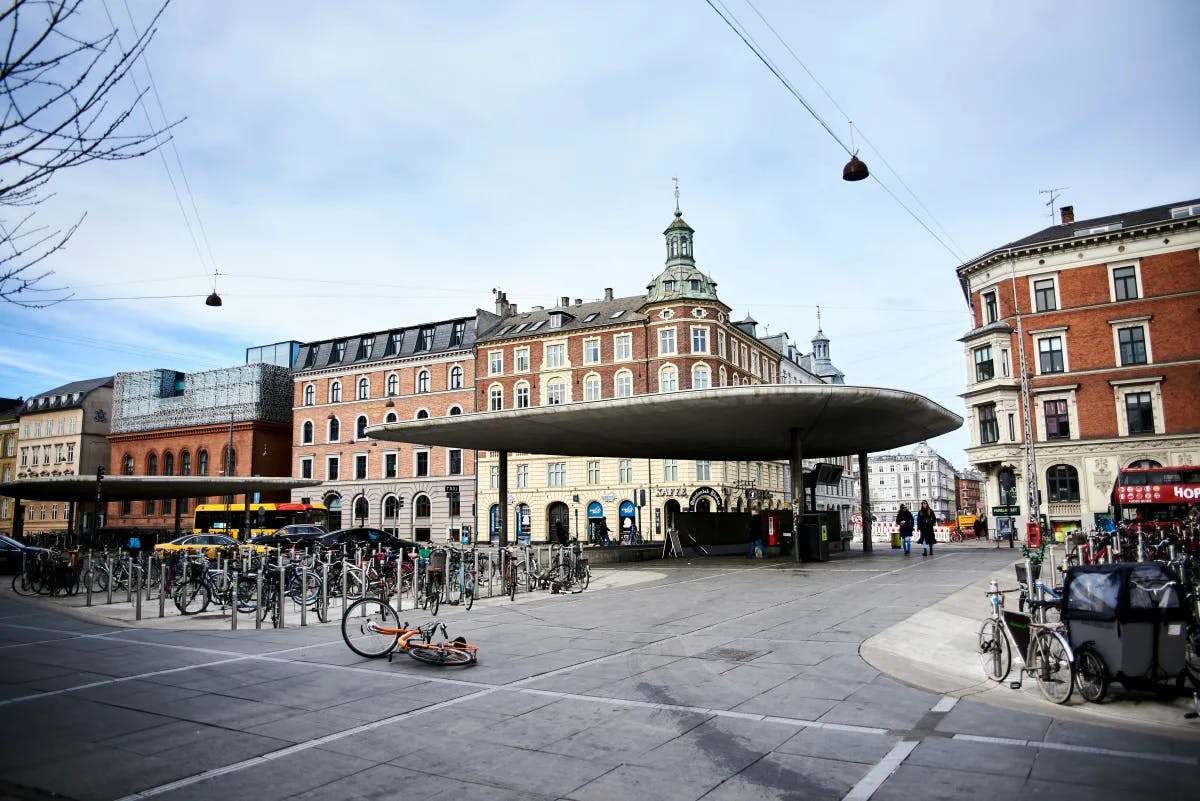 An assortment of bicycles parked on the side of a street with various European style buildings in the surrounding area. 