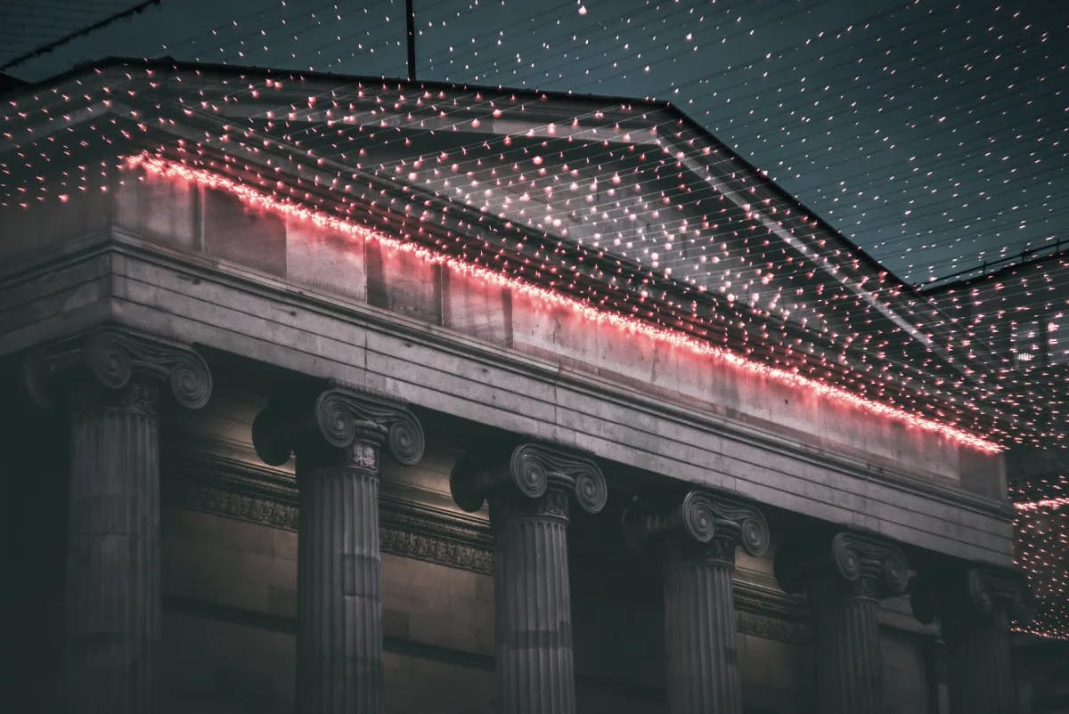 An old white building with pillars and red fairy lights hanging from it in Glasgow.