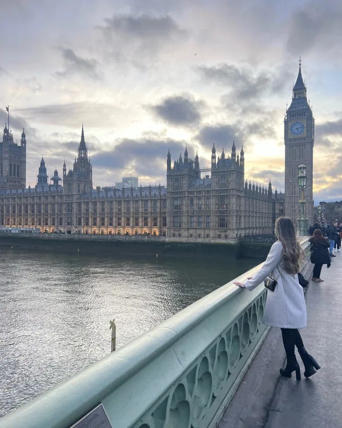 Advisor on a bridge overlooking a view of Big Ben near the water on a cloudy day. 