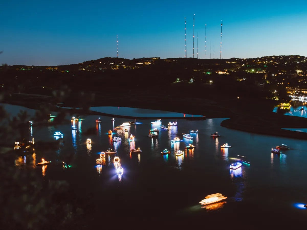 An aerial view of the river during nighttime with multicolored lit-up boats.