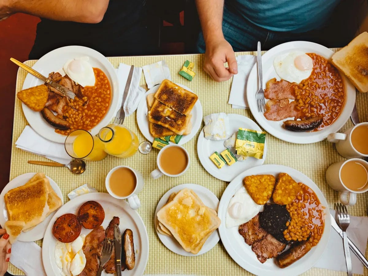 A table with plates of traditional British breakfast, including toast, sausage and beans.