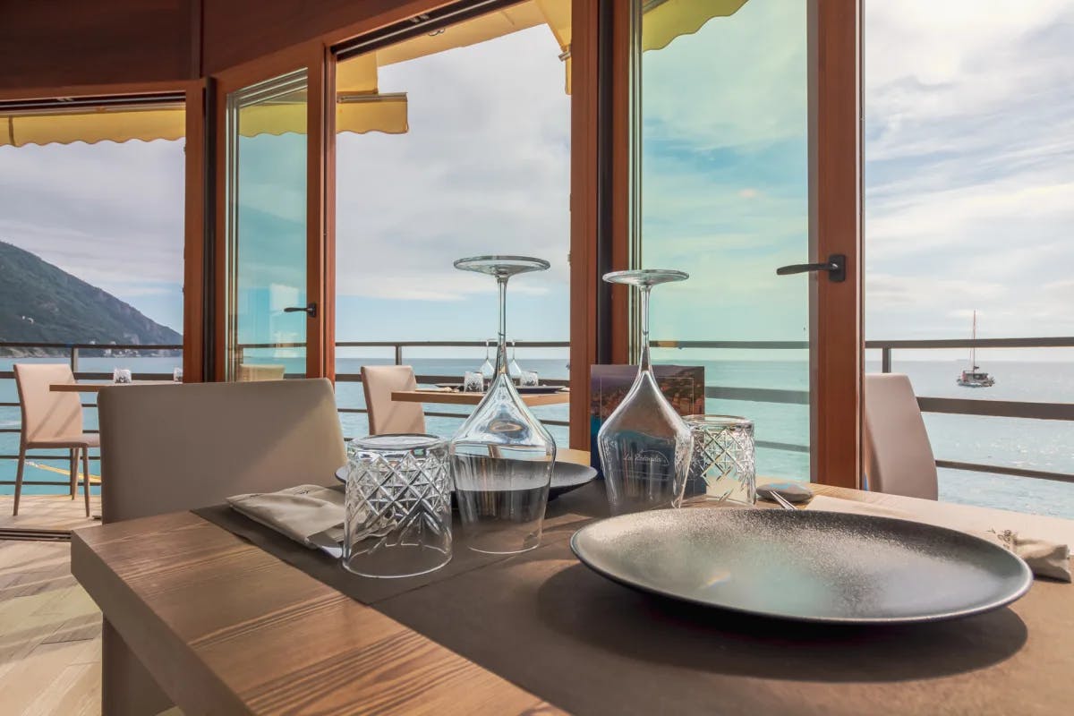 A dining table with upside down glasses, next to glass doors with a view of the water