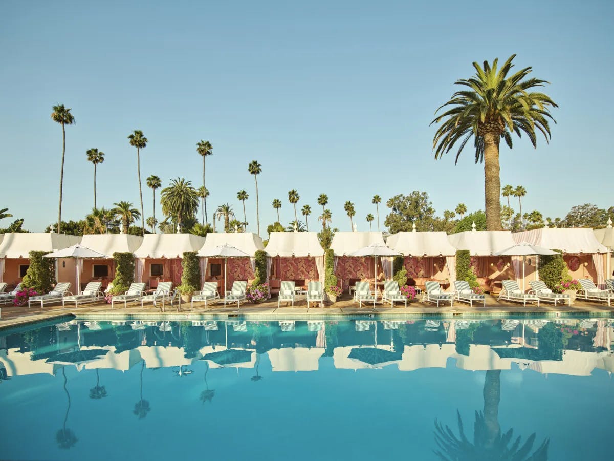 pristine pool flanked by luxe cabanas and palm trees in sunny California