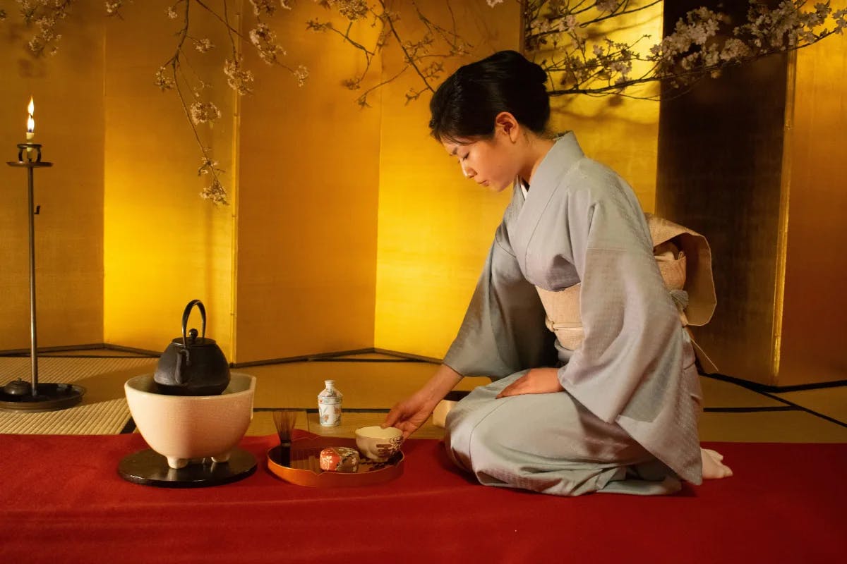 A woman sitting on the floor making traditional tea.