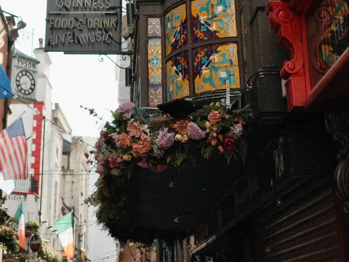 A close-up view of an entrance of a pub with floral decoration and stained glass windows in Dublin.