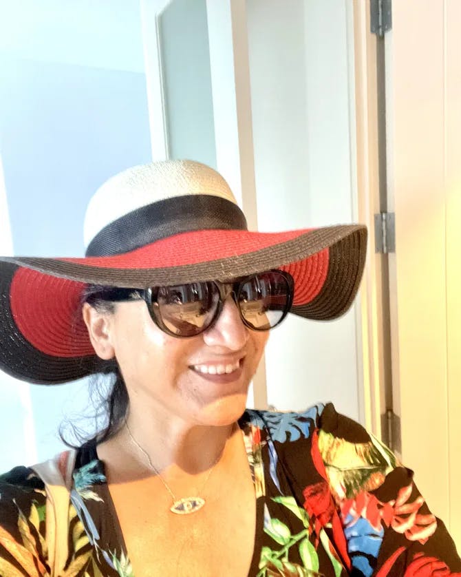 Travel advisor Lisa wearing colorful shirt and red, white and black hat and sunglasses