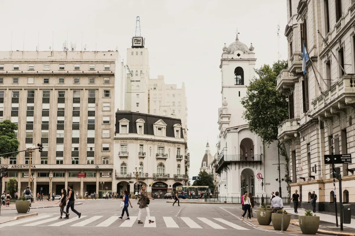 city streets with gray and white buildings and people crossing the street