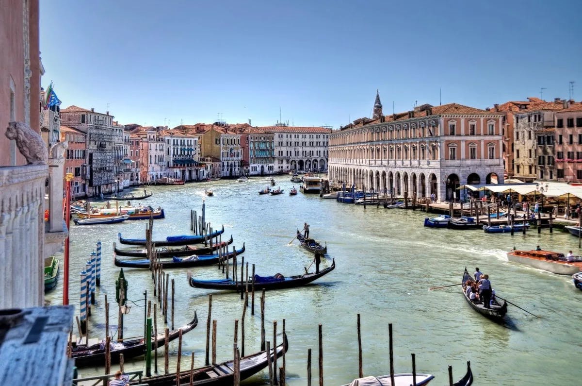 Gondolas in a city canal with buildings around.