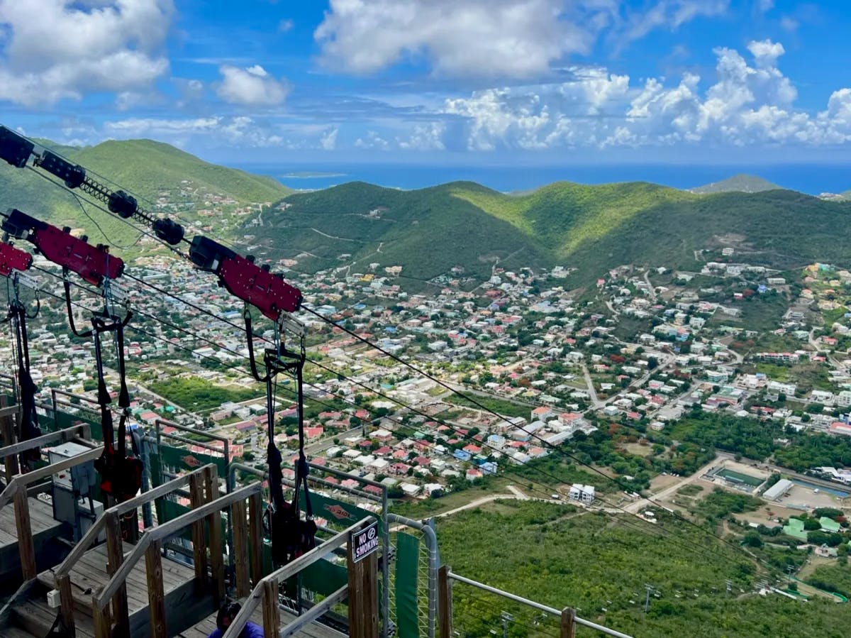 Ziplining with city view of buildings and mountains.