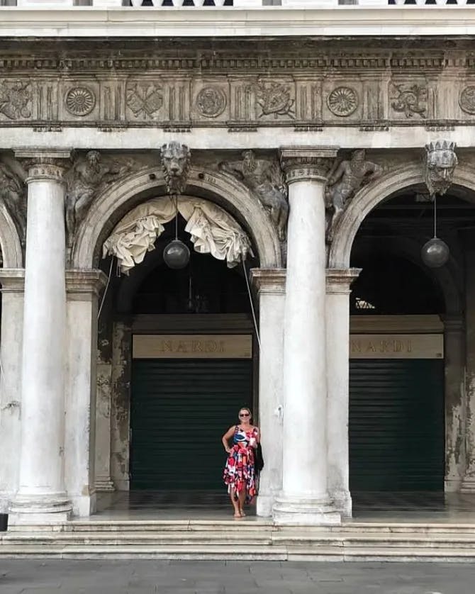 Travel advisor Shannon standing in a colorful dress under arches and pillars in St. Mark's Square plaza