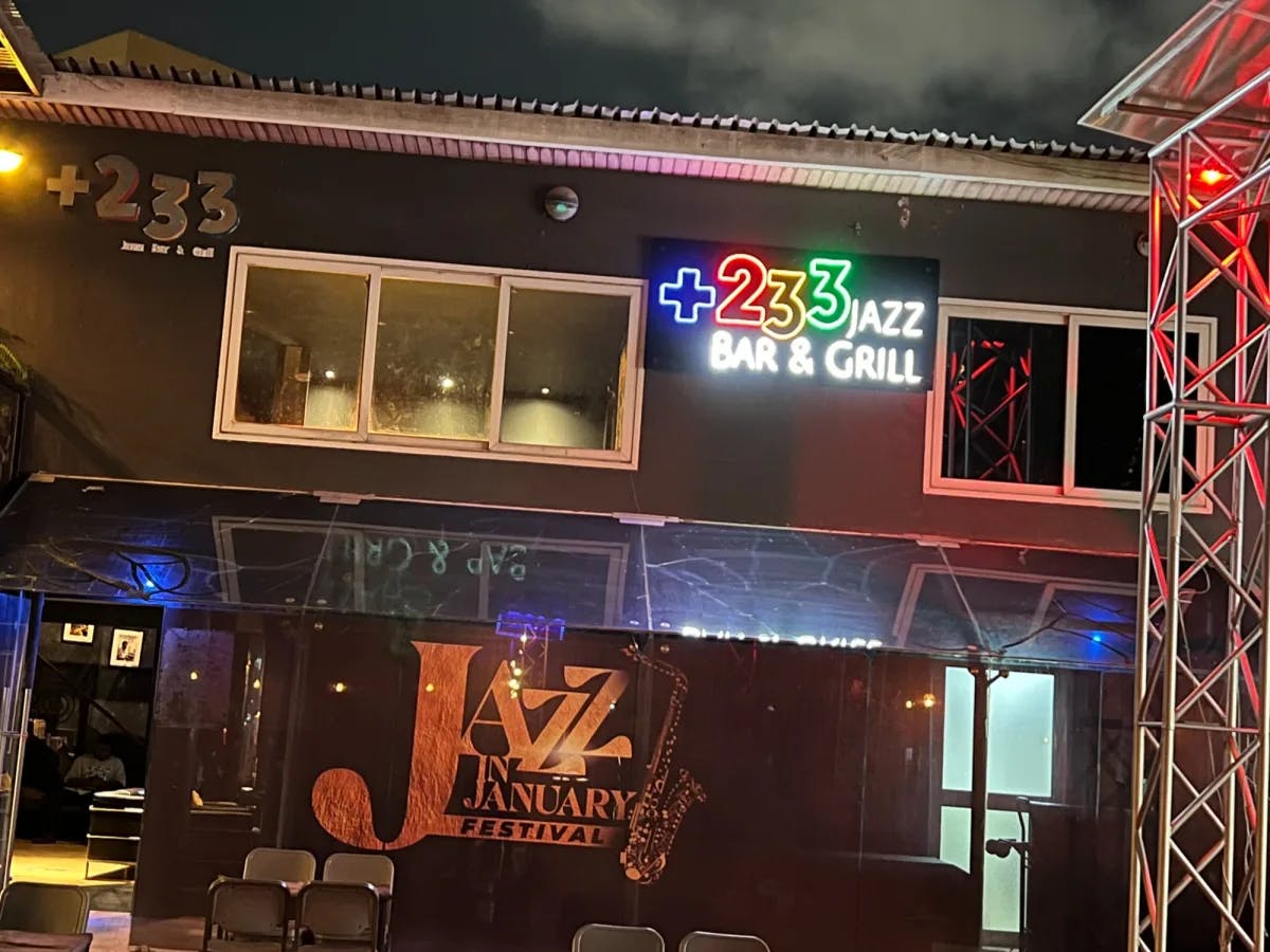 An outdoor patio outside of Club 233, lit up with a neon sign, at night.