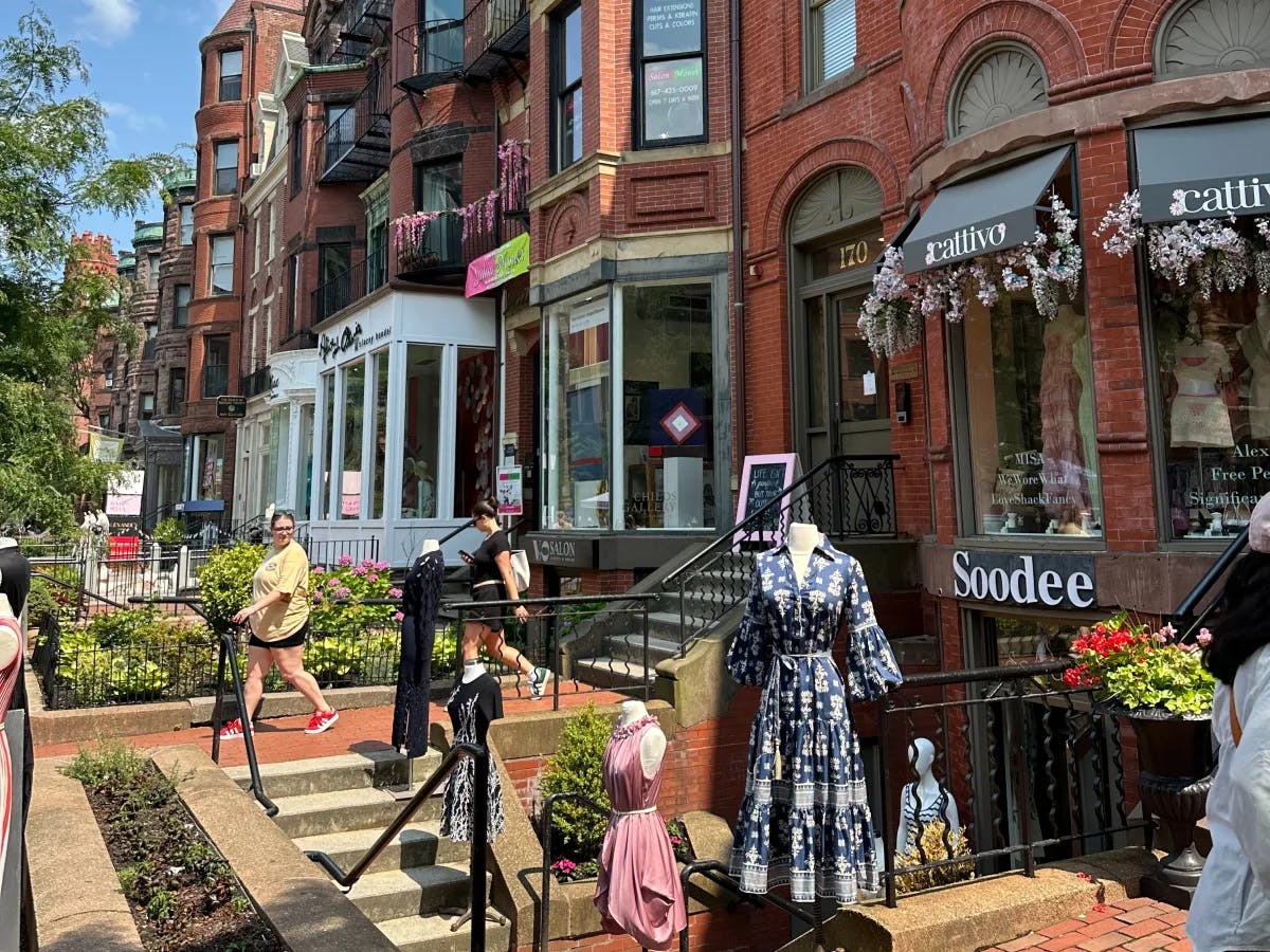 A vibrant street scene with people, colorful brick buildings and storefronts under a clear sky.