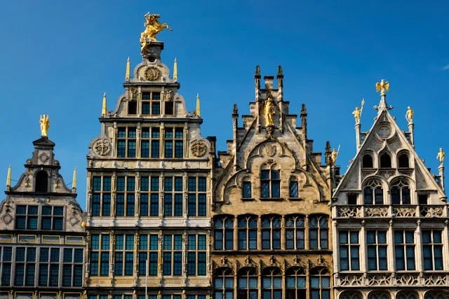 A historic building in Grote Markt, Antwerp, Belgium, with a gold-colored horse statue on the top, on a sunny day. 