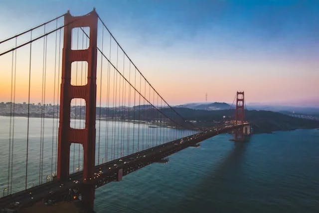 A large red bridge over a body of water during a sunset