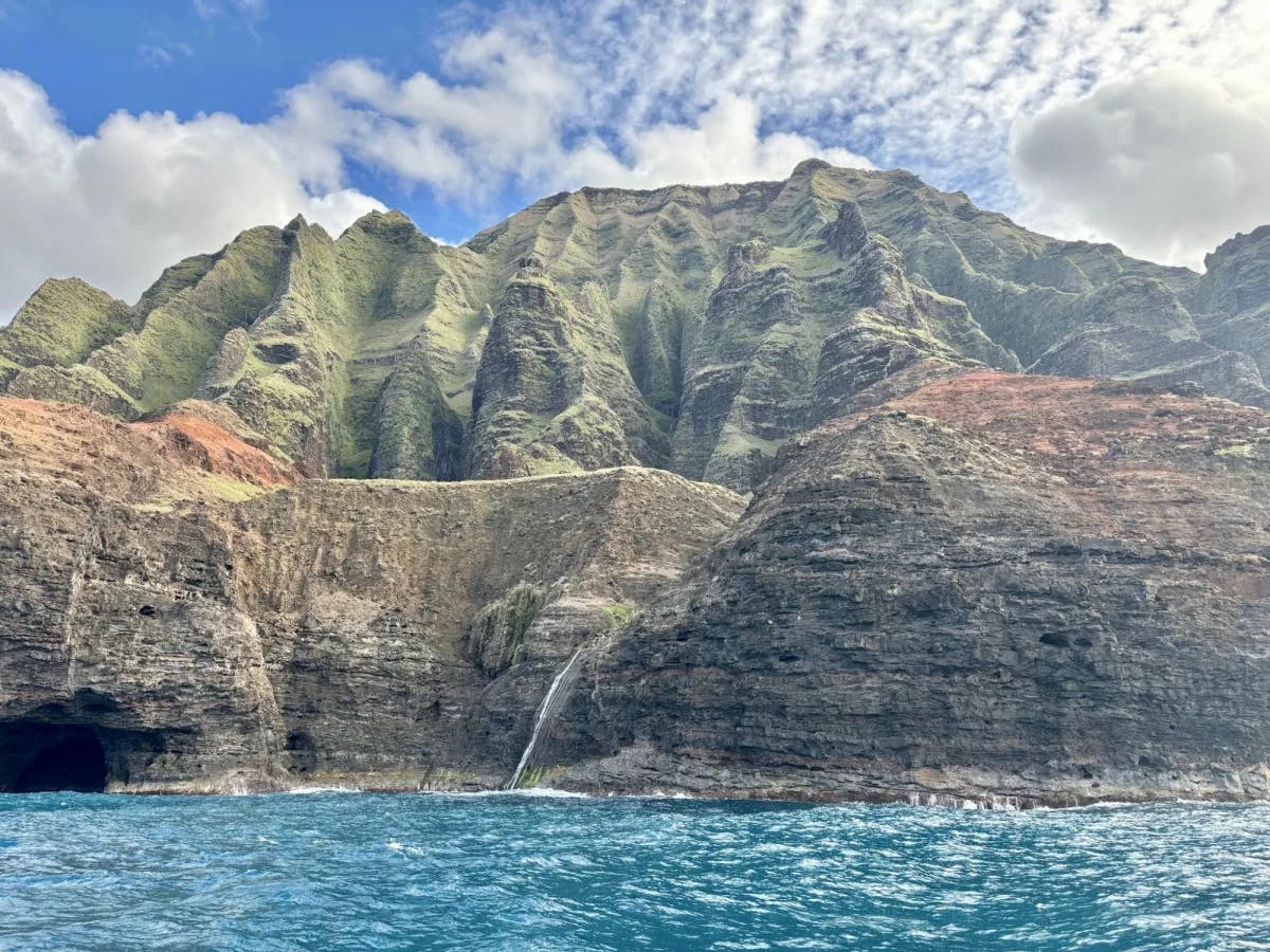 Mountain with ocean during daytime.