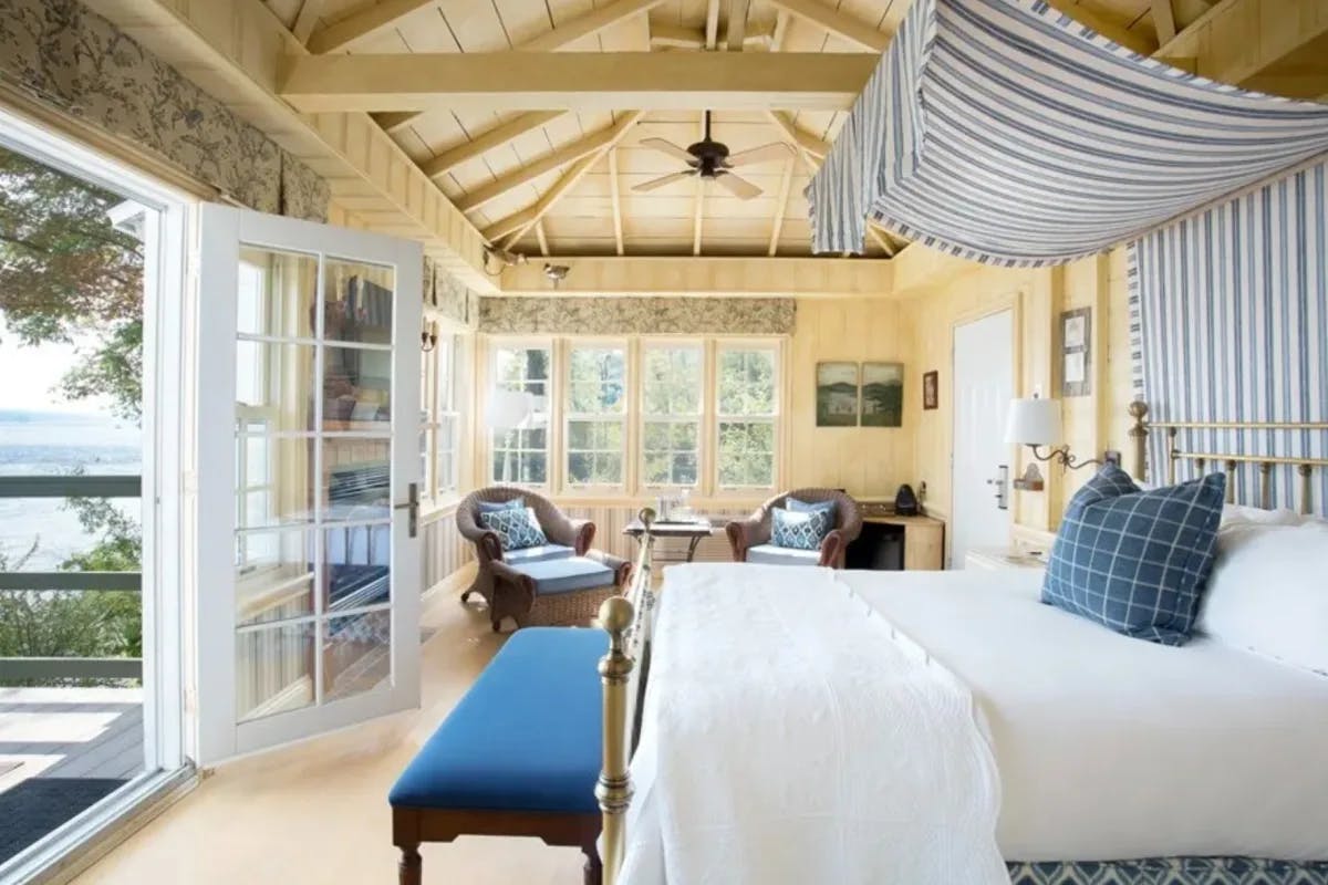 white and blue bedroom with a wooden ceiling and glass doors leading to a deck