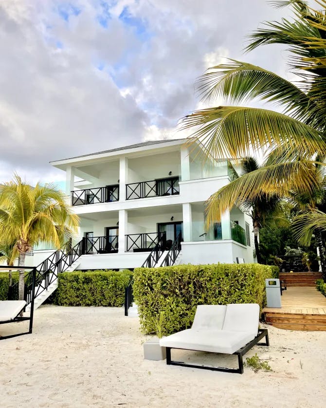 A view of a villa with a seating area and foliage during the daytime.