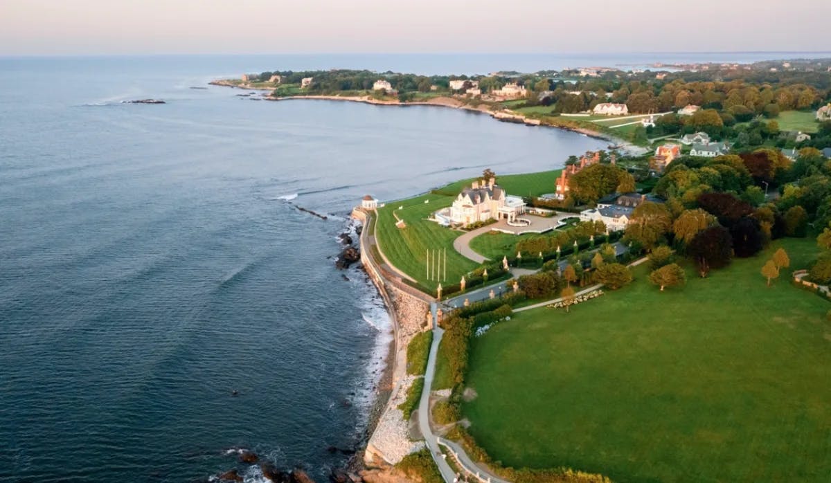 An aerial view of Rhode Island with grass, an estate and the blue ocean.