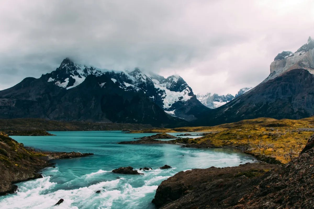 Spring in Patagonia: brilliant turquoise waters buffeted by a rough landscape beneath majestic mountains that are covered with clouds (photo by Diego Jimenez)