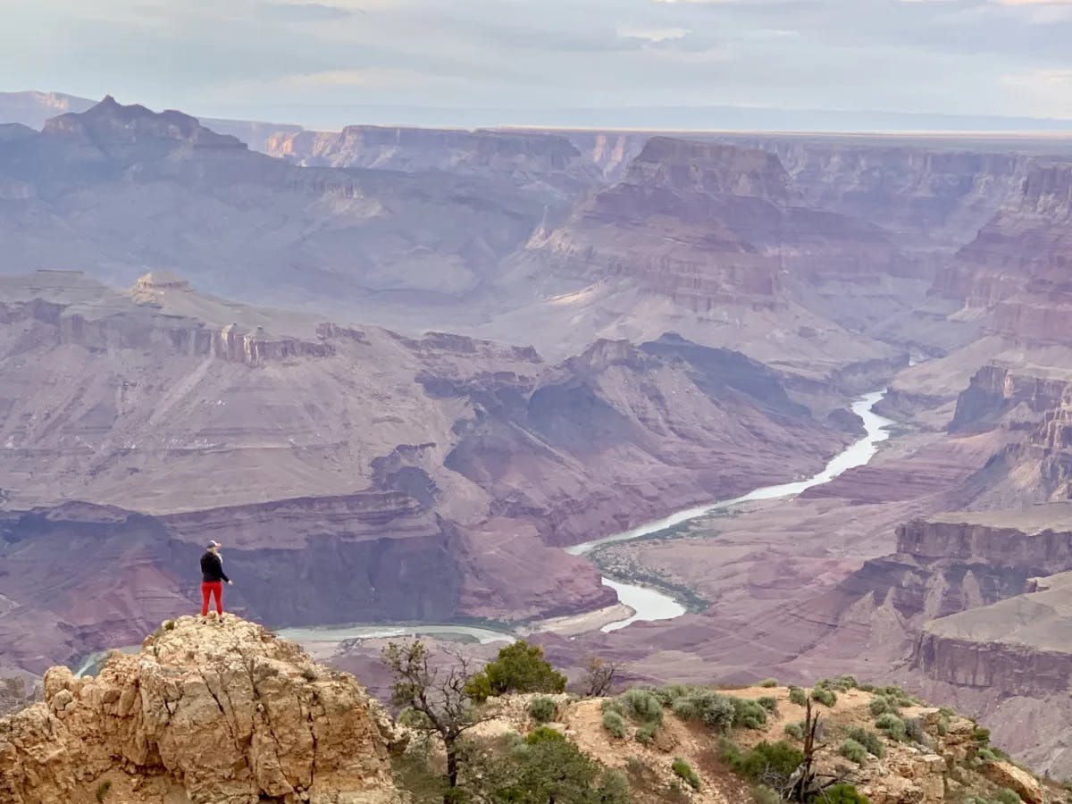 A woman on a cliff looking over canyons.