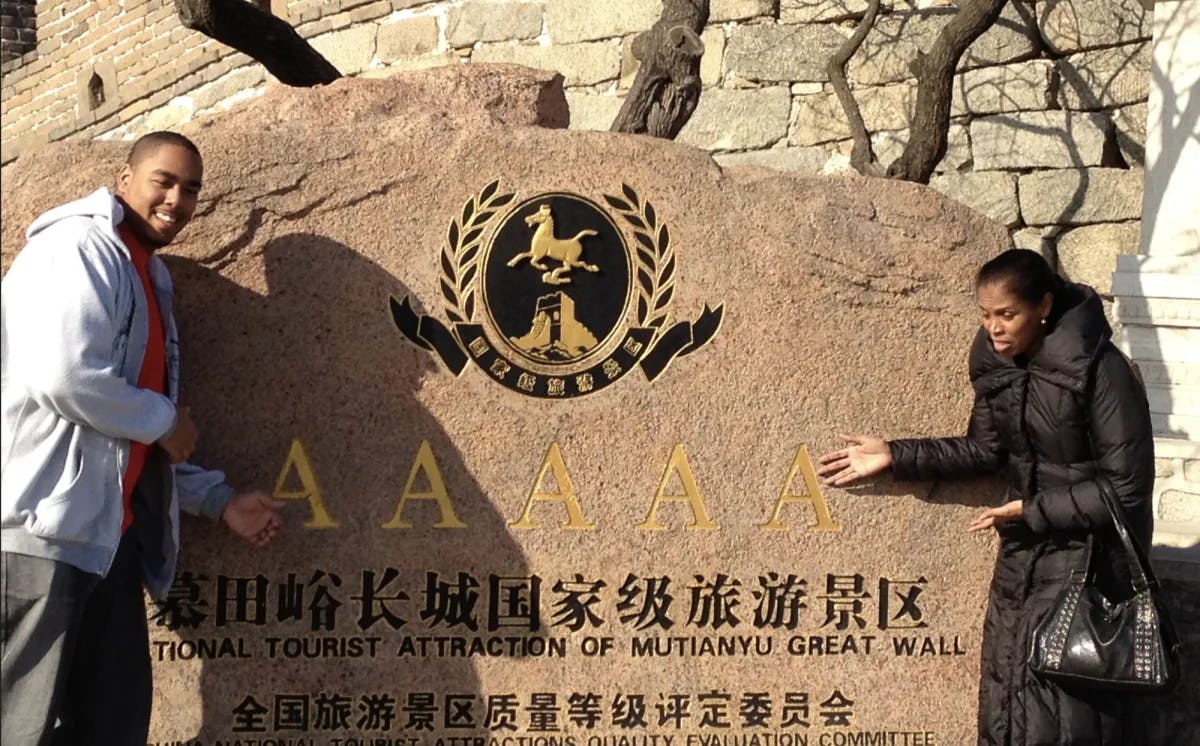 Two people standing next to a rock with the local writing on it 