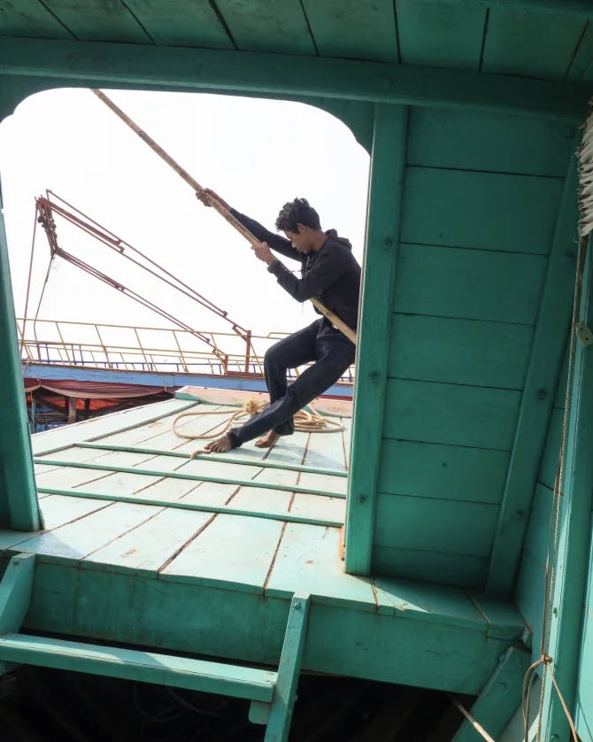 Man pulling the sails of a ship