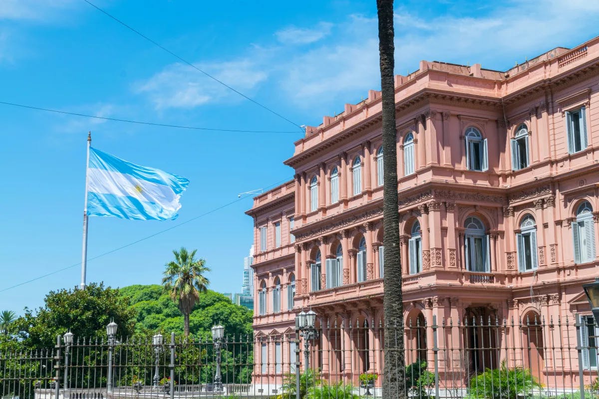 A large, pink building with Argentina's blue and white flag in front of it