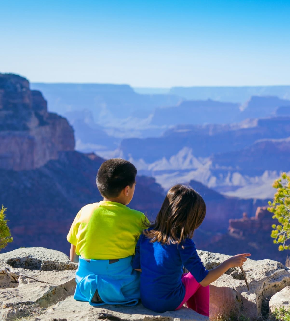 Children sitting on a cliff edge during the daytime