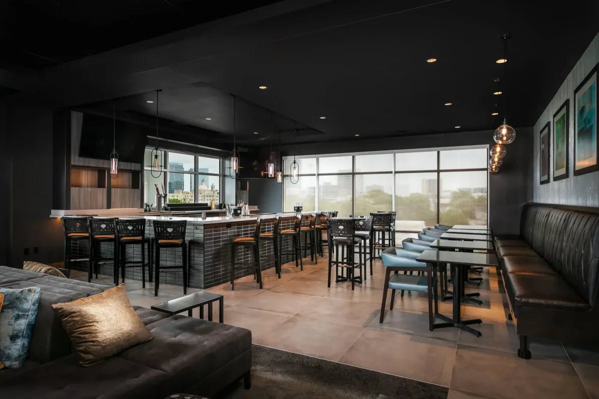 Moody bar at Towneplace Suites By Marriott Nashville Midtown with dim lighting, sleek furniture and black ceilings and walls