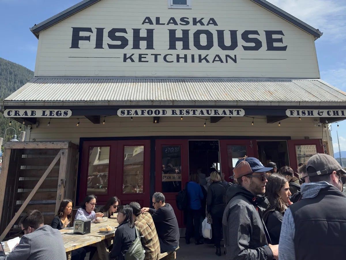 Alaska Fish House's outdoor dining area full of people eating, drinking and waiting to be seated on a sunny day. 