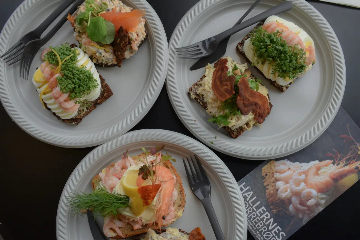 A picture of various meals on toast served on three white plates at a restaurant.