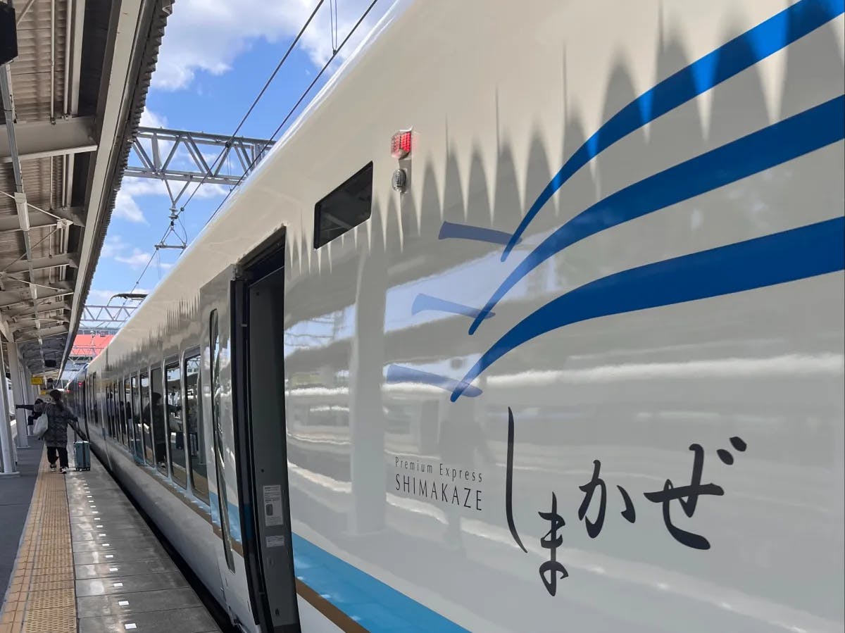 A modern train stationed at a platform with Japanese text on its side.